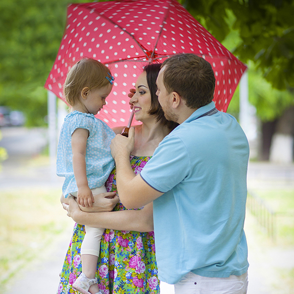 Three individuals under an umbrella